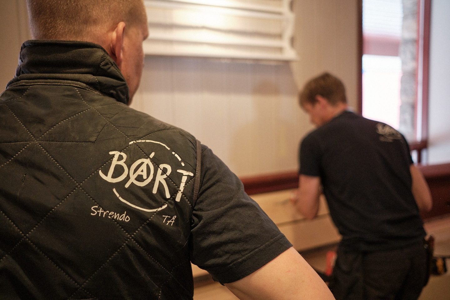 Håndverker sett bakfra med BØRT-logo på jakken, i arbeid med innredning