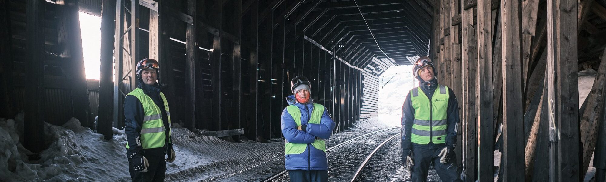 Tre personer i refleksvest inne i snøoverbygget på Bergensbanen